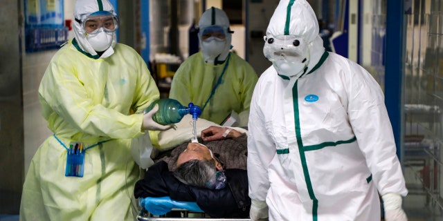 In this Thursday, Feb. 6, 2020, photo, medical workers transfer a patient in the isolation ward for 2019-nCoV patients at a hospital in Wuhan in central China's Hubei province.