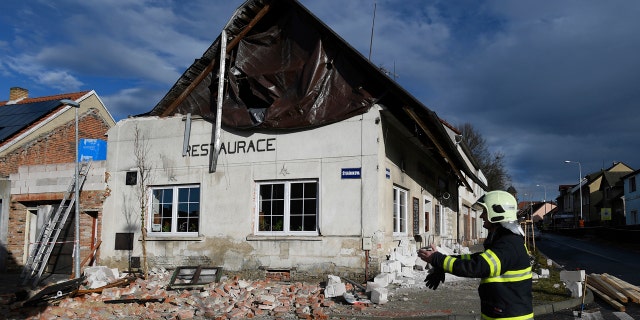 A fireman passes by a house which roof was moved due to a strong storm in Kladno, Czech Republic, Monday, Feb. 10, 2020.