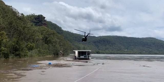 A helicopter touches down on a houseboat in Australia that drifted down a flooded river on Monday.
