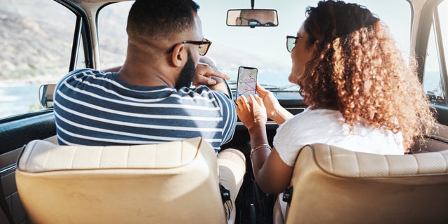 Shot of a young couple using GPS on their mobile phone during a road trip