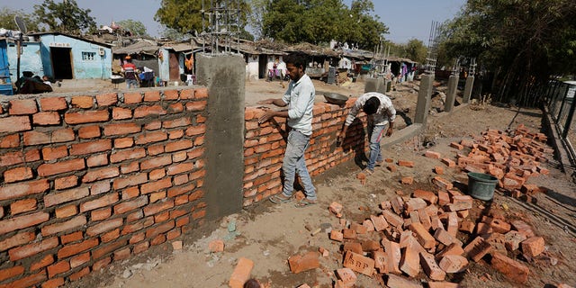 Indian workers construct a wall in front of a slum ahead of U.S. President Donald Trump's visit, in Ahmadabad, India, Monday, Feb. 17, 2020. Trump is scheduled to visit the city during his Feb. 24-25 India trip. (AP Photo/Ajit Solanki)