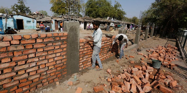 Indian workers construct a wall in front of a slum ahead of U.S. President Donald Trump's visit, in Ahmadabad, India, Monday, Feb. 17, 2020. Trump is scheduled to visit the city during his Feb. 24-25 India trip. (AP Photo/Ajit Solanki)