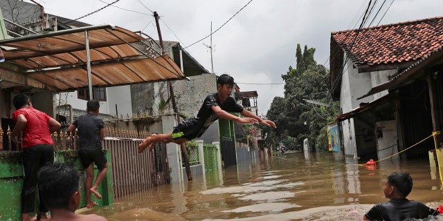Indonesian youths play in flood water in a neighborhood in Jakarta, Indonesia, Tuesday, Feb. 25, 2020.