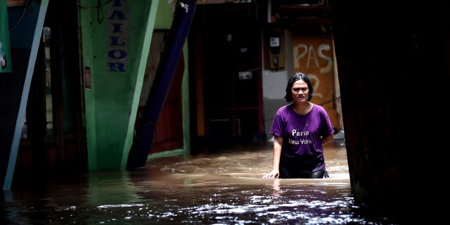 A woman wades through water in a flooded neighborhood in Jakarta, Indonesia, Tuesday, Feb. 25, 2020.