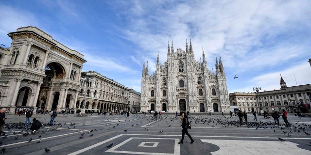A small number of people walk through the usually bustling Piazza Duomo in Milan on Wednesday. (Claudio Furlan/LaPresse via AP)