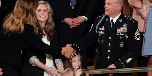 As Amy Williams watches, her husband Sgt. 1st Class Townsend Williams, greets first Lady Melania Trump after he surprised her by appearing at the State of the Union address by President Donald Trump in a joint session of Congress on Capitol Hill in Washington, Tuesday, Feb. 4, 2020. Their children Rowan, 3, and Elliana, watch. (AP Photo/J. Scott Applewhite)