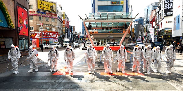 South Korean army soldiers wearing protective suits spray disinfectant to prevent the spread of the COVID-19 virus on a street in Daegu.