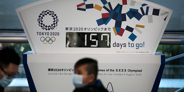 Two people wearing masks sit in front of a countdown clock for the Tokyo 2020 Olympics on Tuesday. Tokyo Olympic organizers said last week there is no "Plan B" for the 2020 Games, which open in just over five months and have been jolted by the outbreak of the coronavirus in neighboring China.