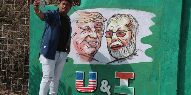 A man takes a selfie with portraits of U.S. President Donald Trump and Indian Prime Minister Narendra Modi painted on a wall ahead of Trump's visit, in Ahmadabad, India, Tuesday, Feb. 18, 2020. Trump is scheduled to visit the city during his Feb. 24-25 India trip. [AP Photo/Ajit Solanki)