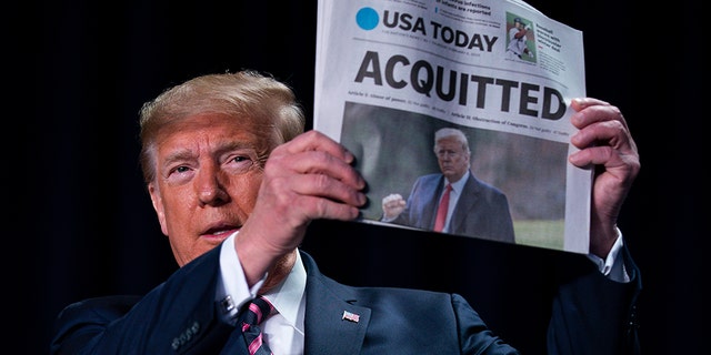 President Trump holds up a newspaper with the headline that reads "ACQUITTED" at the 68th annual National Prayer Breakfast, at the Washington Hilton, Thursday, Feb. 6, 2020, in Washington. (AP Photo/ Evan Vucci)