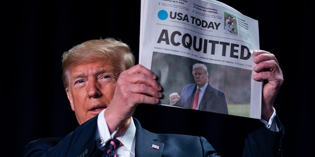 President Trump holds up a newspaper with the headline that reads "ACQUITTED" at the 68th annual National Prayer Breakfast, at the Washington Hilton, Thursday, Feb. 6, 2020, in Washington. (AP Photo/ Evan Vucci)