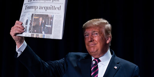 President Donald Trump holds up a newspaper with the headline that reads "Trump acquitted" during the 68th annual National Prayer Breakfast, at the Washington Hilton, Thursday, Feb. 6, 2020, in Washington. (AP Photo/ Evan Vucci)