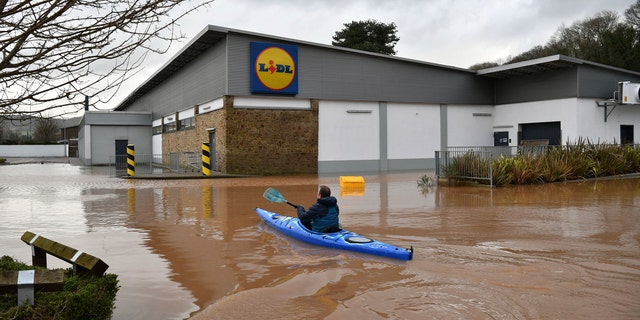 A man travels by boat through floodwater in Monmouth, Wales, Tuesday Feb. 18, 2020.