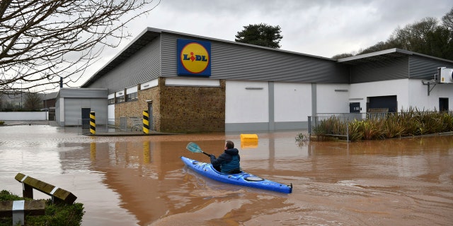 A man travels by boat through floodwater in Monmouth, Wales, Tuesday Feb. 18, 2020.