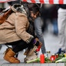 A woman sets a candle near the hookah bar scene where several people were killed late Wednesday in Hanau, Germany, Feb. 20, 2020.