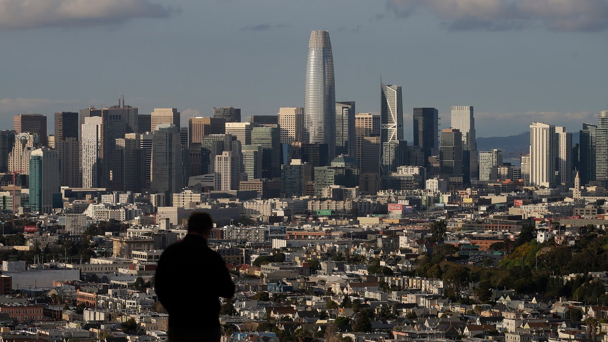 A man looks toward the skyline from Bernal Heights Hill in San Francisco, Monday, March 16, 2020. (AP Photo/Jeff Chiu)