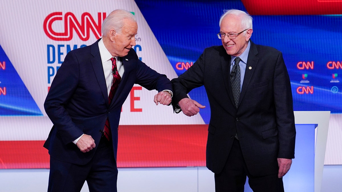 Former Vice President Joe Biden, left, and Sen. Bernie Sanders, I-Vt., right, greet one another before they participate in a Democratic presidential primary debate at CNN Studios in Washington, Sunday, March 15, 2020. (AP Photo/Evan Vucci)