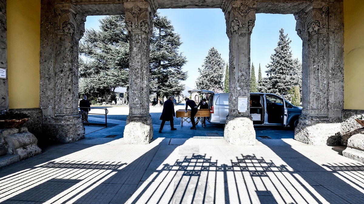 Undertakers carry a coffin out of a hearse at Bergamo's cemetery, northern Italy, Monday, March 16, 2020. Bergamo is one of the cities most hit by the new coronavirus outbreak in northern Italy. (Claudio Furlan/LaPresse via AP)