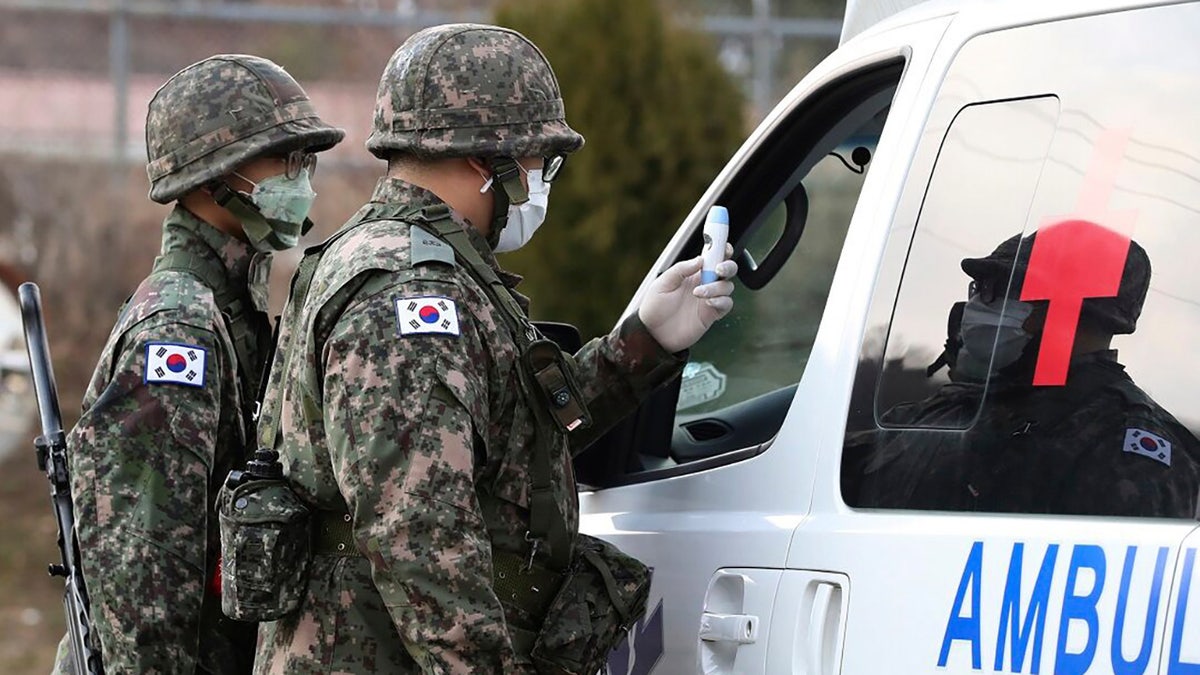 South Korean army soldiers wearing face masks check the temperature of a driver at a checkpoint of a military base in Daegu, South Korea on Wednesday, February 26. Military exercises between South Korean and American forces have been postponed over concerns about the virus. (Ryu Hyung-seok/Yonhap via AP)