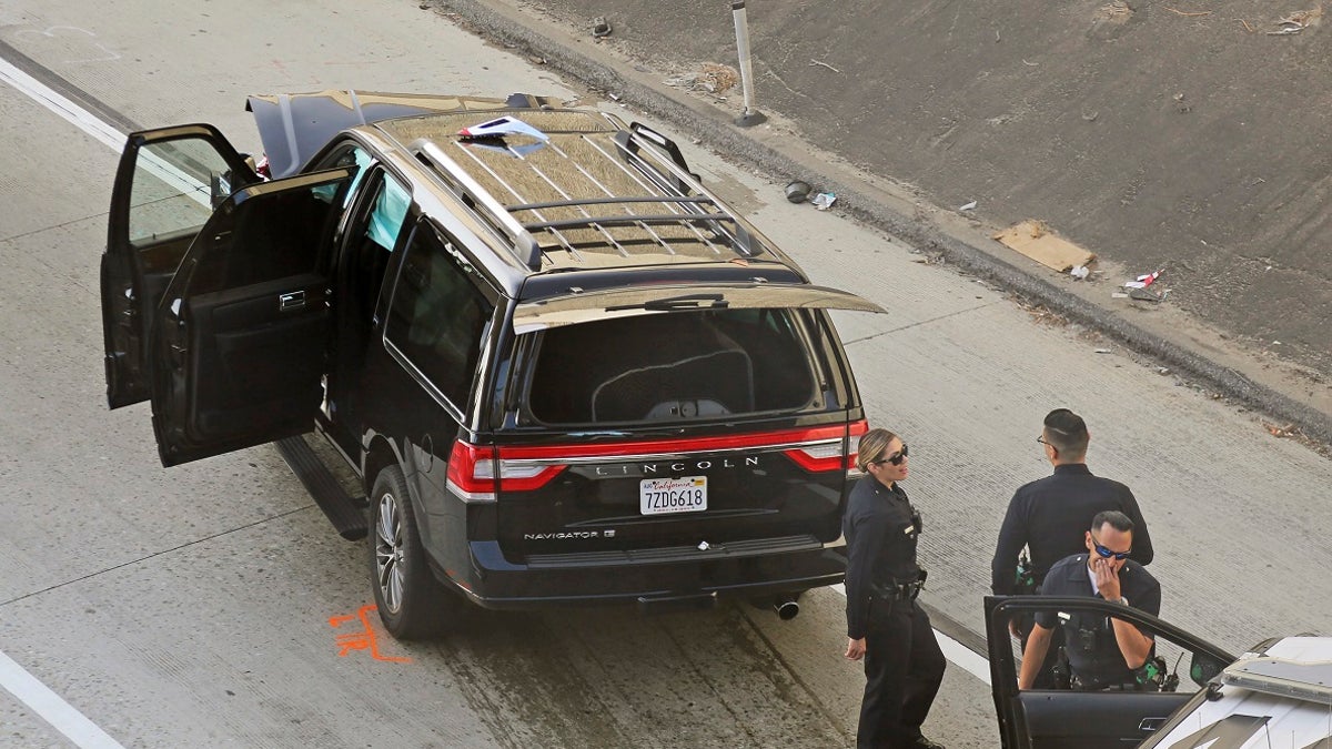 Los Angeles police officers stand after a pursuit of a stolen hearse with a casket and body inside on Interstate 110 in South Los Angeles last week. The hearse was stolen from outside a Greek Orthodox church in East Pasadena on Wednesday night. (AP Photo/Reed Saxon)