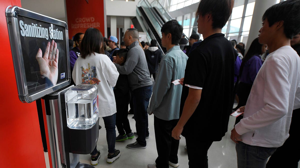 Fans walk by a sanitizing station at Staples Center prior to an NBA basketball game between the Los Angeles Clippers and the Philadelphia 76ers Sunday, March 1, 2020, in Los Angeles. (AP Photo/Mark J. Terrill)