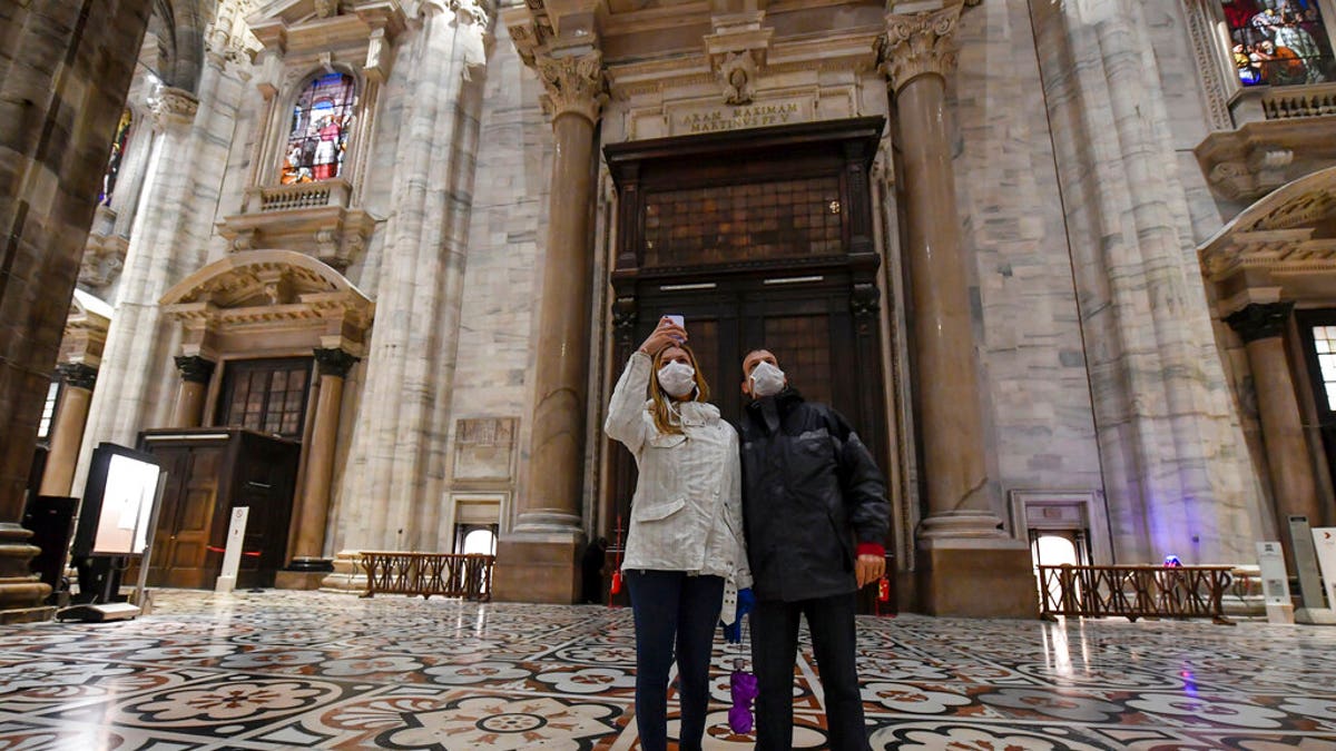 Tourits wearing face masks take pictures inside the Duomo gothic cathedral as it reopened to the public after being closed due to the COVID-19 virus outbreak in northern Italy, in Milan, Monday, March 2, 2020. 