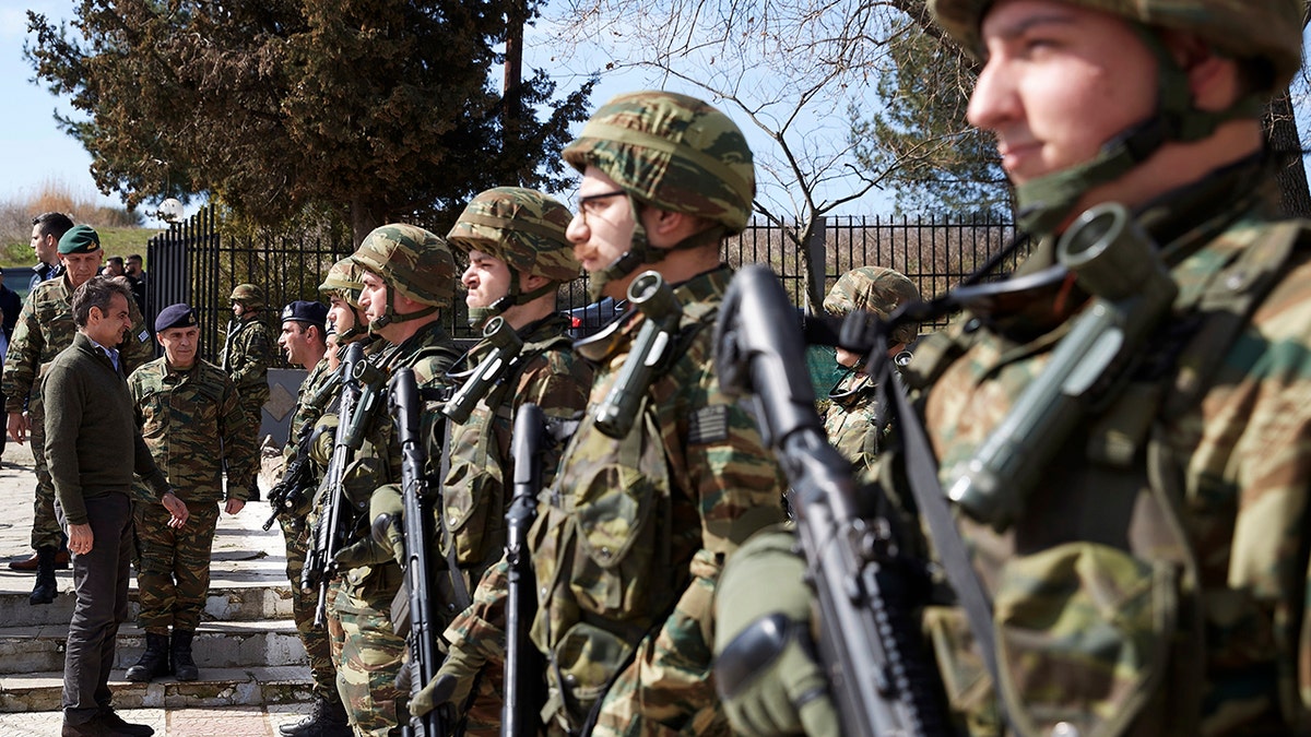 Greece's Prime Minister Kyriakos Mitsotakis, left, reviews Greek soldiers guard at the Kipoi border gate, Evros region, at the Greek-Turkish border on Tuesday, March 3, 2020. Migrants and refugees hoping to enter Greece from Turkey appeared to be fanning out across a broader swathe of the roughly 200-kilometer-long land border Tuesday, maintaining pressure on the frontier after Ankara declared its borders with the European Union open. (Dimitris Papamitsos/Greek Prime Minister's Office via AP)