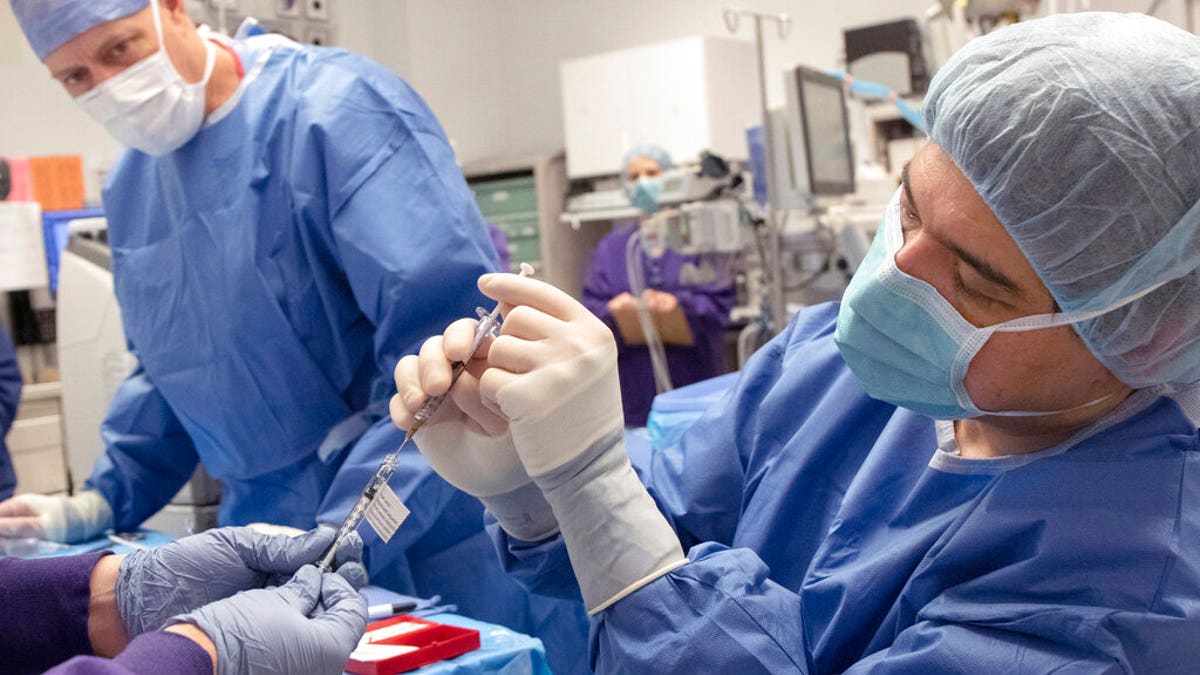 Dr. Andreas Lauer, right, prepares to perform the first-ever in vivo CRISPR gene edit procedure for the BRILLIANCE clinical trial at the school's Casey Eye Institute in Portland, on a patient who had an inherited form of blindness. I