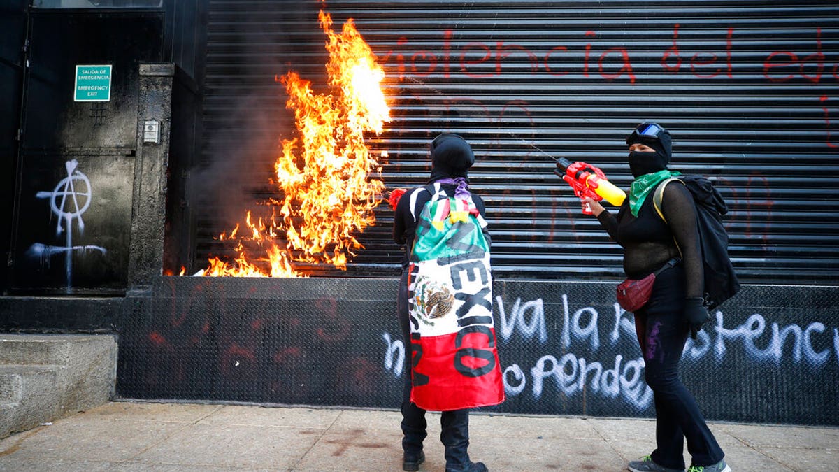 Demonstrators set fire to the entrance of a building during a march for International Women's Day in Mexico City, Sunday, March 8, 2020.
