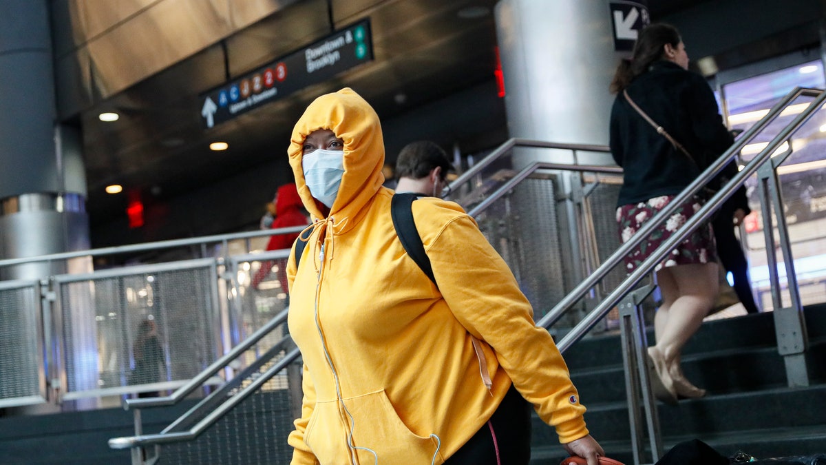 A commuter wears a face mask in the New York City transit system, Monday, March 9, 2020, in New York. New York continued grappling Monday with the new coronavirus, as case numbers, school closings and other consequences grew. (AP Photo/John Minchillo)