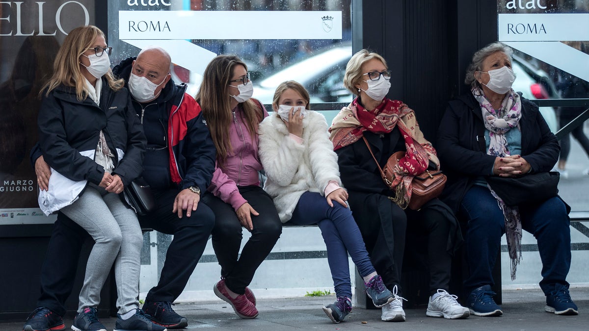 People wait at a bus stop, in Rome, Monday, March 9, 2020. Italy announced a sweeping quarantine early Sunday for its northern regions, igniting travel chaos as it restricted the movements of a quarter of its population in a bid to halt the new coronavirus' relentless march across Europe. (Roberto Monaldo/LaPresse via AP)