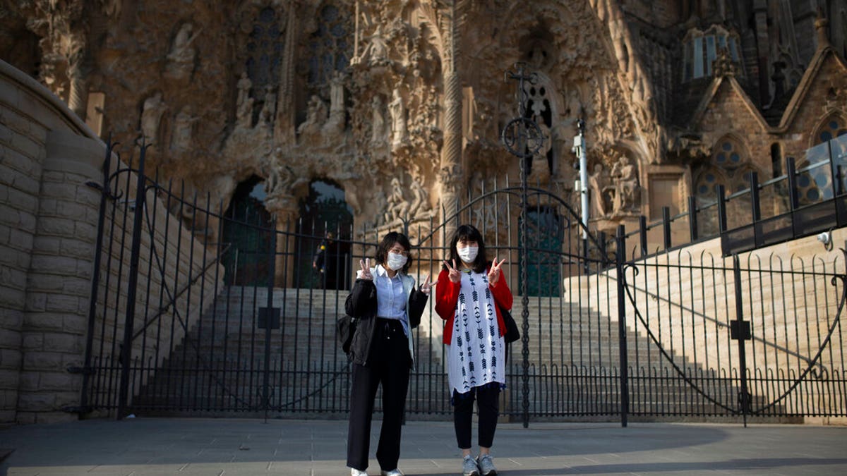 Tourists pose for a photo outside the Sagrada Familia basilica in Barcelona, Spain, Friday, March 13, 2020. The basilica closed its doors to visitors and suspend construction from Friday March 13 to prevent the spread of the new COVID-19 coronavirus. Spain, along with Italy and France, is among the countries worst hit by the virus so far in Europe.