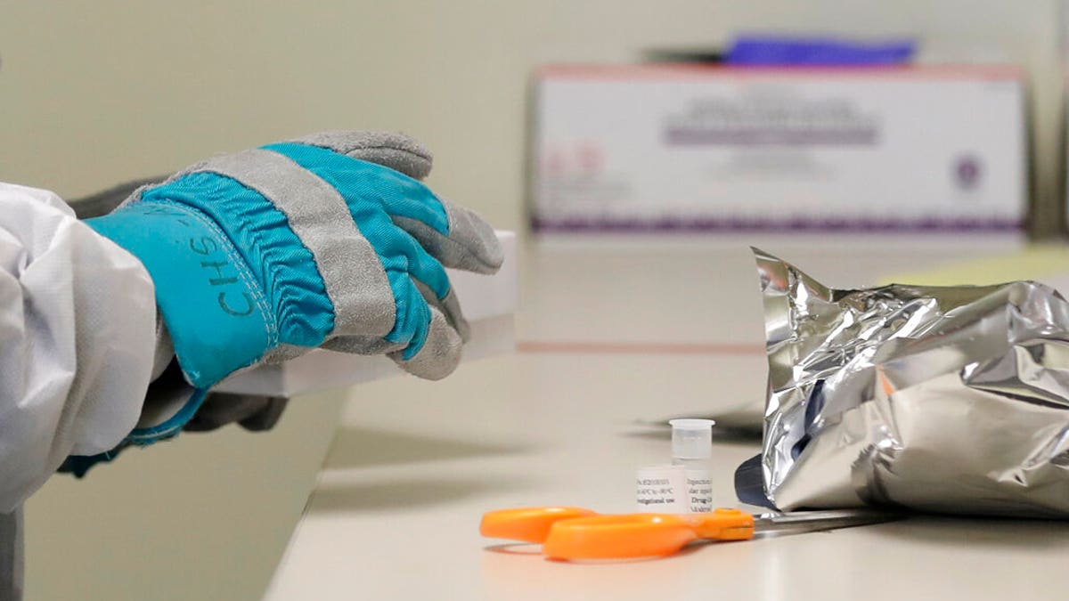 Pharmacist Michael Witte wears heavy gloves as he opens a frozen package of the potential vaccine for COVID-19, the disease caused by the new coronavirus, on the first day of a first-stage safety study clinical trial, Monday, at the Kaiser Permanente Washington Health Research Institute in Seattle. (AP Photo/Ted S. Warren)