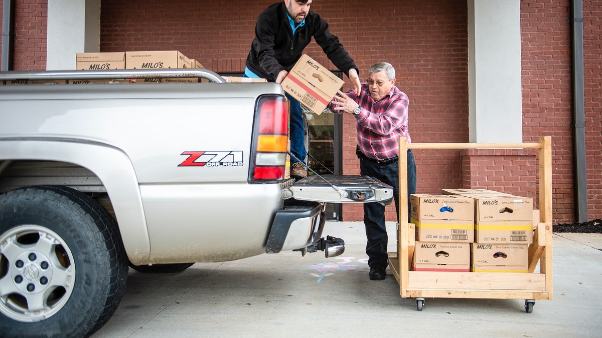 Josh Howard, left, and Ken Runager load boxes of food to be sent to Chestnut Grove Elementary at The Church at Stone River on Monday, March 16, 2020, in Decatur, Ala. Several area schools will be providing food services to students starting Wednesday after students transition to virtual support. (Dan Busey/The Decatur Daily via AP)
