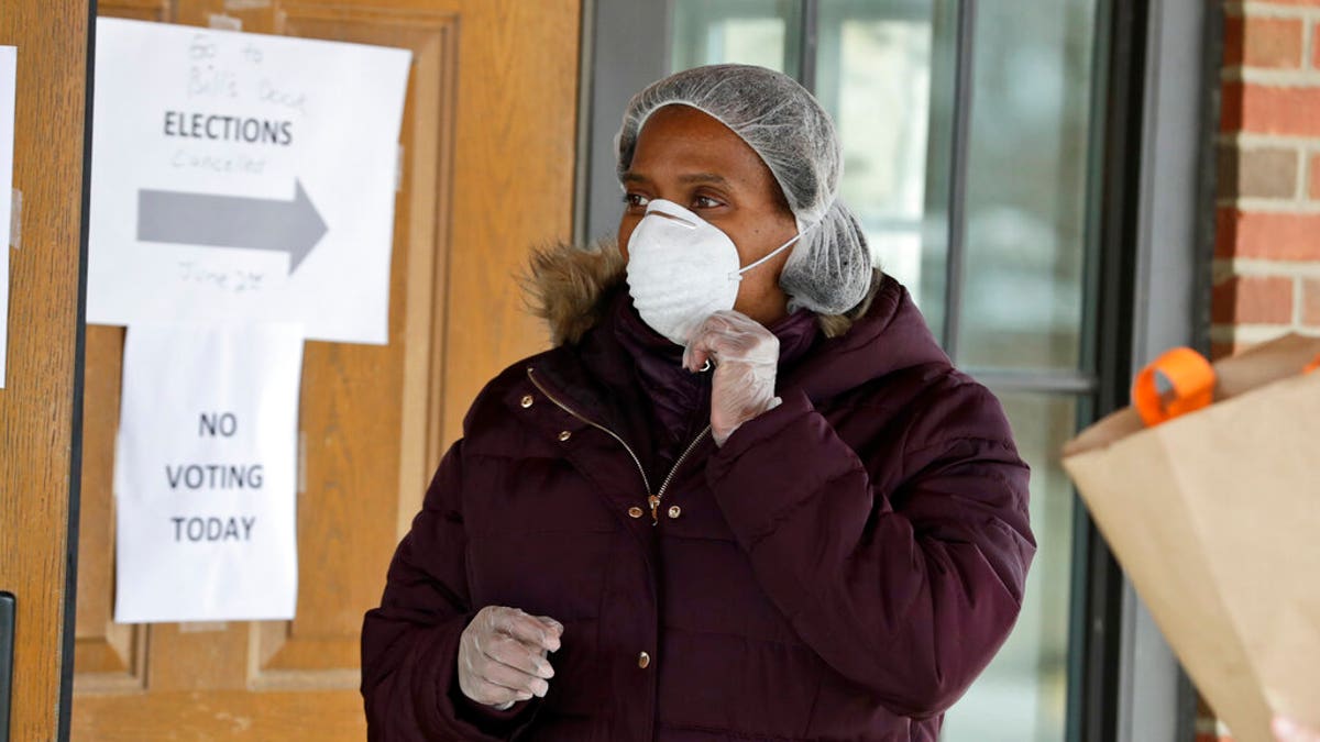 Sylka Edmondson talks with a senior citizen at the Lakefront Community Center, an Ohio polling center, Tuesday, March 17, 2020, in Euclid, Ohio. (AP Photo/Tony Dejak)