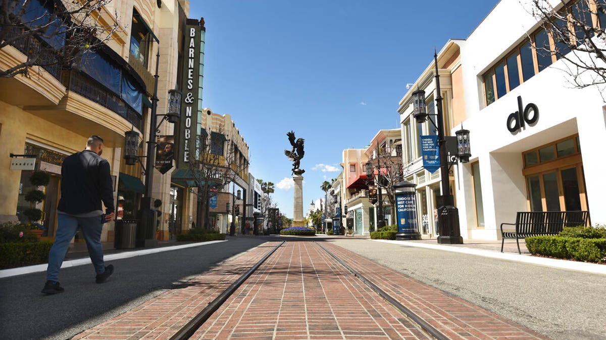 A visitor to the shopping and entertainment complex The Grove walks down a deserted street Wednesday, March 18, 2020, in Los Angeles. 