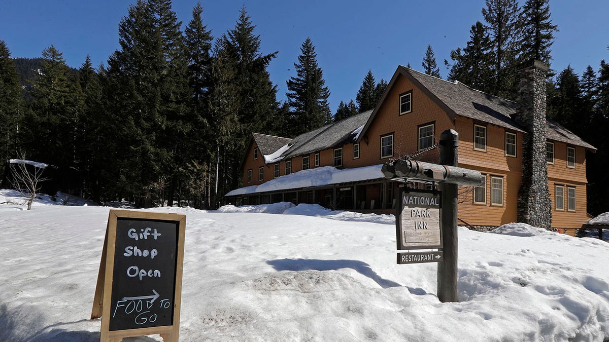 A sign at the National Park Inn at Longmire offers food orders to-go from the inn's restaurant at Mount Rainier National Park, Wednesday, March 18, 2020, in Washington state. Most national parks are remaining open during the outbreak of the new coronavirus, but many are closing visitor centers, shuttles, lodges and restaurants in hopes of containing its spread. (AP Photo/Ted S. Warren)