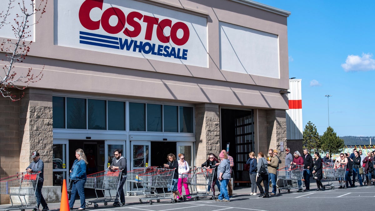At the Costco in Spokane Valley, Wash., the store is practicing social distancing by limiting how many customers can be in the store at one time. A line wrapped around the building on March 20, but was moving so that the wait was only around 10 to 15 minutes. (Colin Mulvany/The Spokesman-Review via AP)