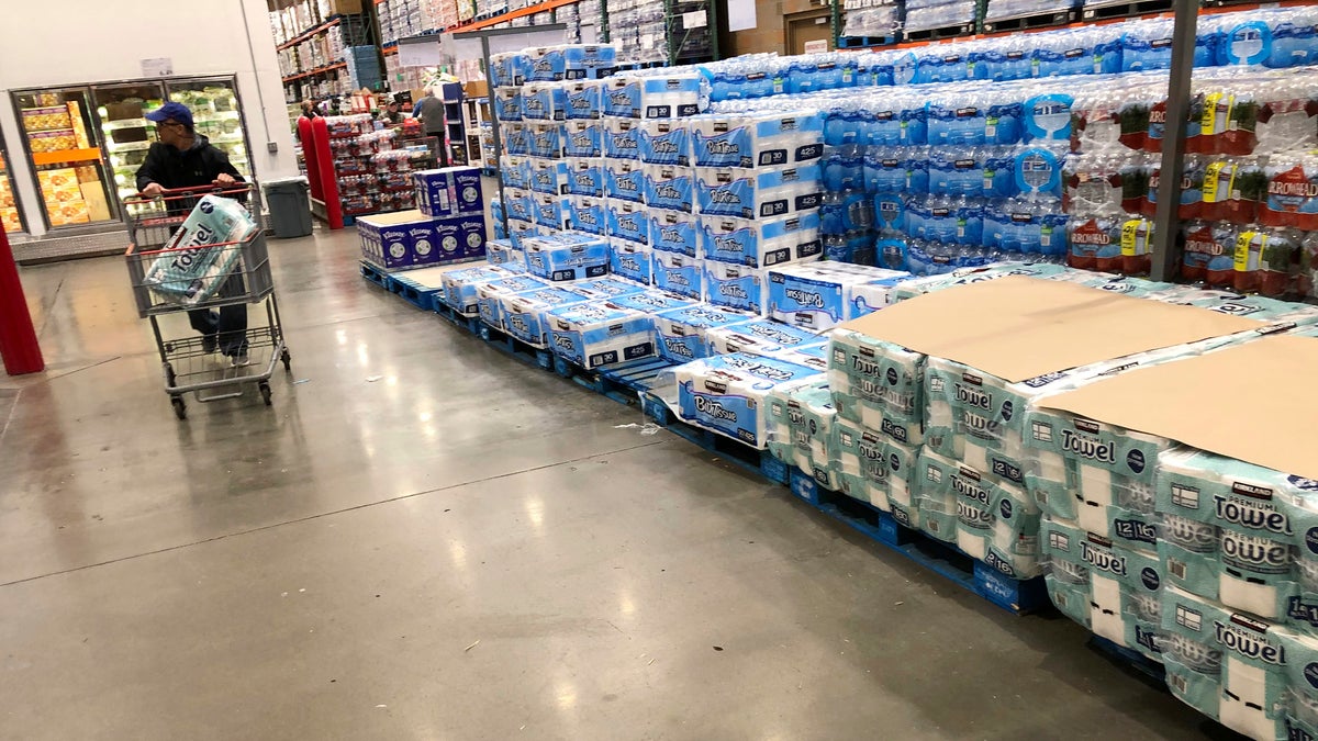A shopper pushes a cart past a dwindling supply of toilet paper and hand towels in a Costco warehouse as shoppers continue to buy paper products in response to the spread of the coronavirus on March 23 in Lone Tree, Colo. (AP Photo/David Zalubowski)