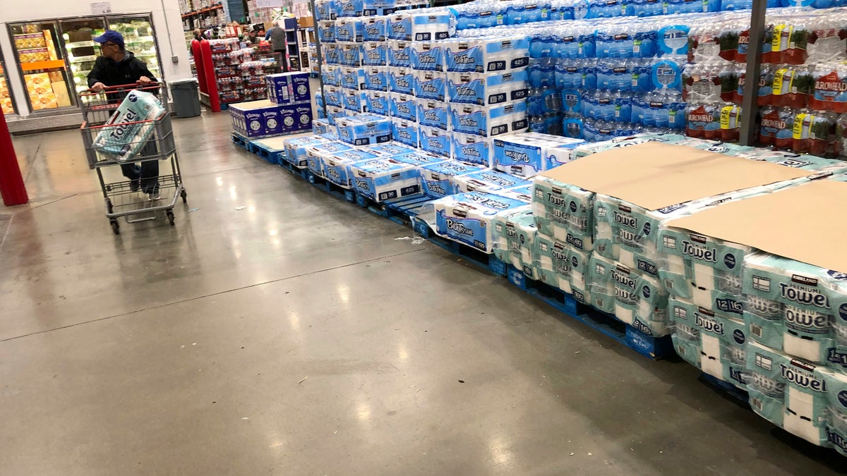 A shopper pushes a cart past a dwindling supply of toilet paper and hand towels in a Costco warehouse as shoppers continue to buy paper products in response to the spread of the coronavirus on March 23 in Lone Tree, Colo. (AP Photo/David Zalubowski)