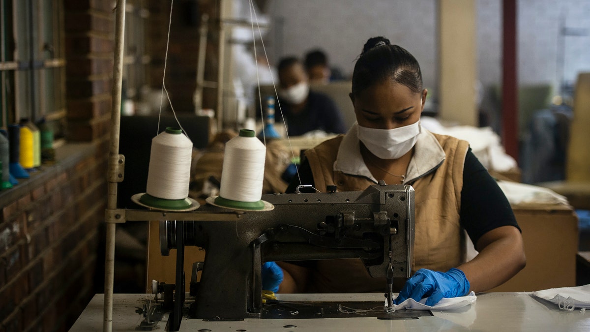 A woman sews high-quality face masks at a furniture factory in Eldorado Park, Johannesburg. (AP Photo/Shiraaz Mohamed)