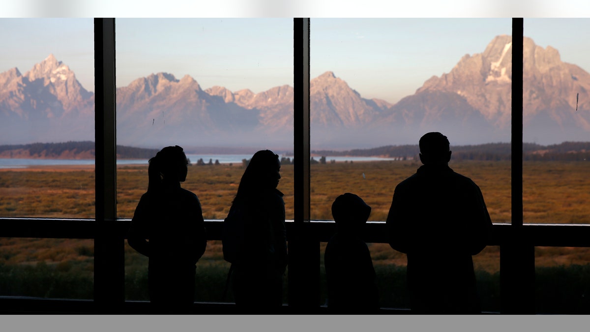 FILE - In this Aug. 28, 2016 file photo, visitors watch the morning sun illuminate the Grand Tetons from within the Great Room at the Jackson Lake Lodge in Grand Teton National Park, north of Jackson, Wyo. (AP Photo/Brennan Linsley)