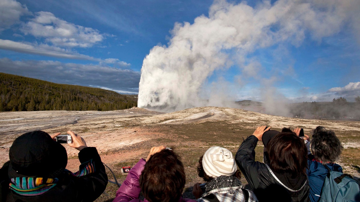 Tourists photograph Old Faithful erupting on schedule late in the afternoon in Yellowstone National Park, Wyo. (AP Photo/Julie Jacobson, File)