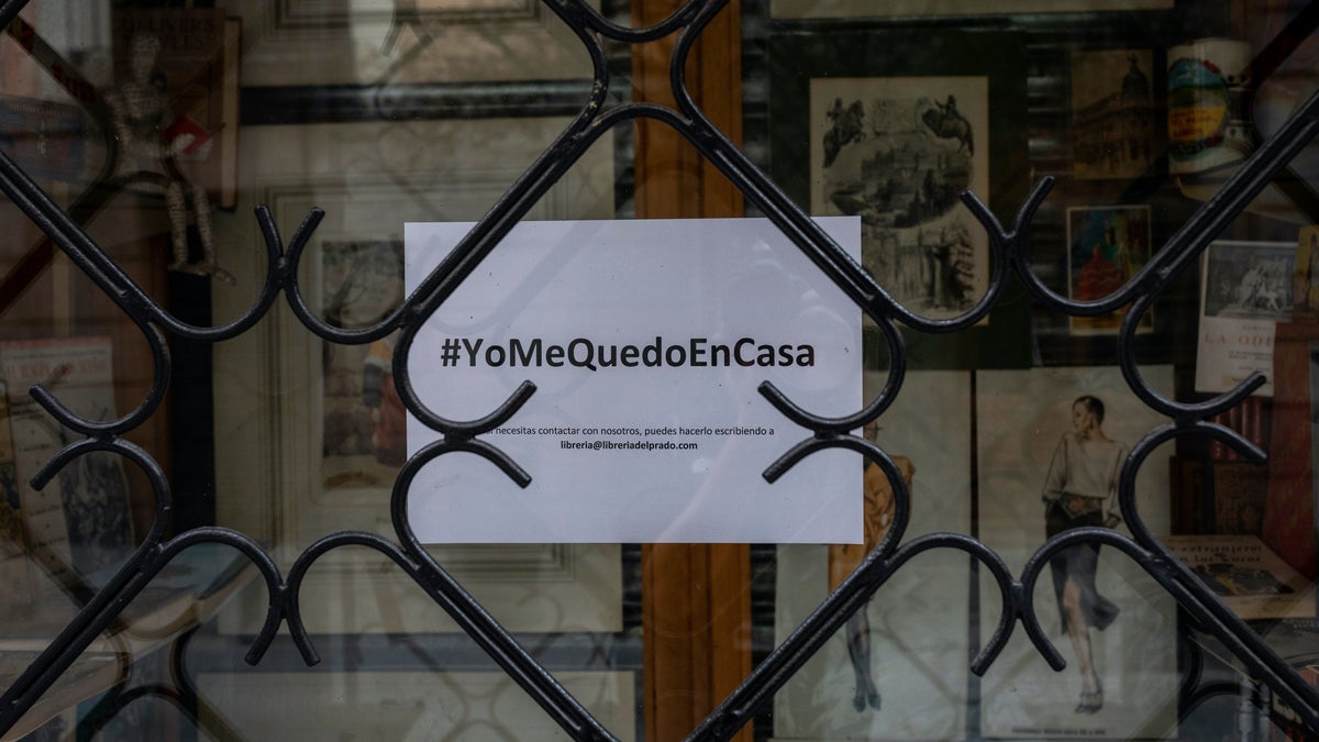 A poster reading in Spanish the hashtag "#IstayAtHome" hangs in windowshop of a closed shop in downtown Madrid, Spain, Tuesday, March 24, 2020. More than 1.5 billion around the world have been told to stay in their homes.