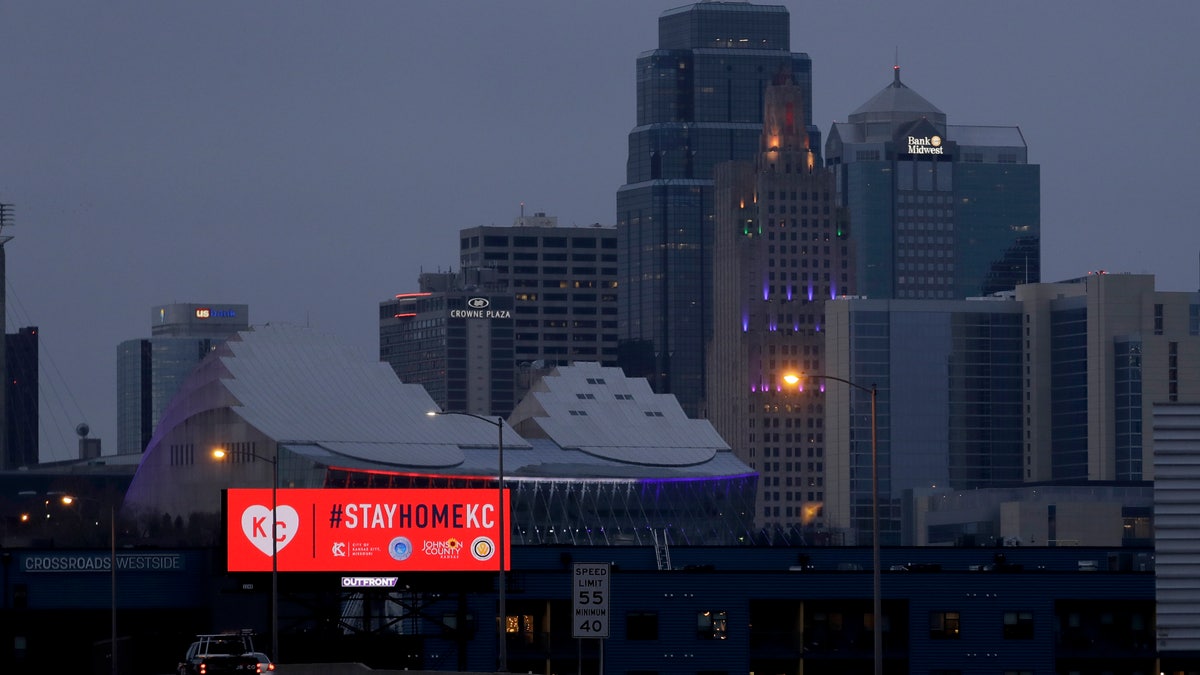 A sign urges residents to stay home as motorists drive past downtown Tuesday, March 24, 2020 on the first day of a stay-at-home order in Kansas City, Mo. Kansas City and surrounding counties instituted a 30-day mandatory stay-at-home order in an effort to stem the spread of the coronavirus. (AP Photo/Charlie Riedel)