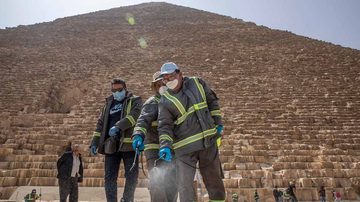 Municipal workers sanitize the walkways around the Giza pyramid complex on Wednesday in hopes of curbing the spread of the new coronavirus outbreak in Egypt. (AP Photo/Nariman El-Mofty)