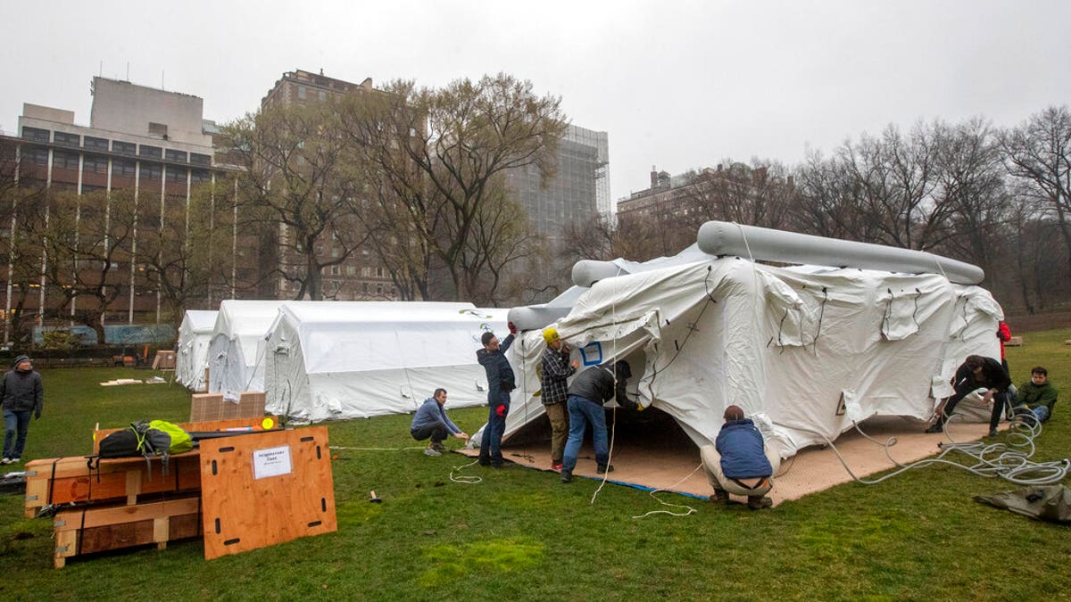 A Samaritan's Purse crew works on building an emergency field hospital equipped with a respiratory unit in New York's Central Park across from the Mount Sinai Hospital, Sunday, March 29, 2020. (AP Photo/Mary Altaffer)