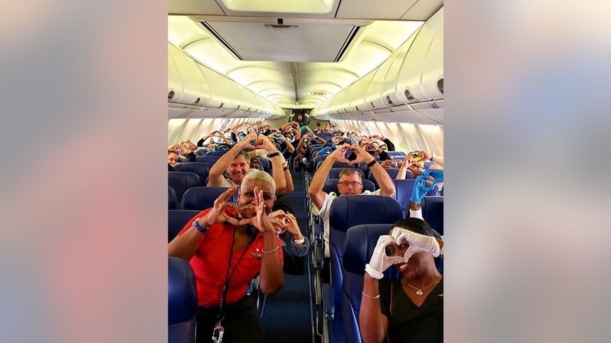 This photo provided by Southwest Airlines employee Dayartra Etheridge shows health care workers, other passengers and flight crew aboard a Southwest flight from Atlanta to New York's LaGuardia Airport holding their hands in the shape of a heart, before the plane pushed back from the gate, at Hartsfield-Jackson Atlanta International Airport.