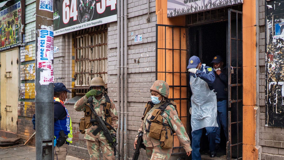 South African police and National Defense Forces search a local bar they though was illegally open in downtown Johannesburg on Monday March 30, 2020. South Africa went into a nationwide lockdown for 21 days in an effort to control the spread of the coronavirus, and patrols have increased in the streets to enforce the lockdown. The new coronavirus causes mild or moderate symptoms for most people, but for some, especially older adults and people with existing health problems, it can cause more severe illness or death.(AP Photo/Jerome Delay)