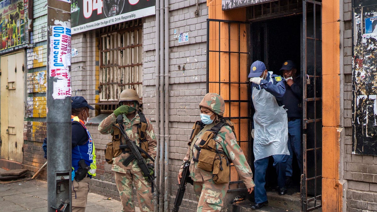 South African police and National Defense Forces search a local bar they though was illegally open in downtown Johannesburg on Monday March 30, 2020. South Africa went into a nationwide lockdown for 21 days in an effort to control the spread of the coronavirus, and patrols have increased in the streets to enforce the lockdown. The new coronavirus causes mild or moderate symptoms for most people, but for some, especially older adults and people with existing health problems, it can cause more severe illness or death.(AP Photo/Jerome Delay)